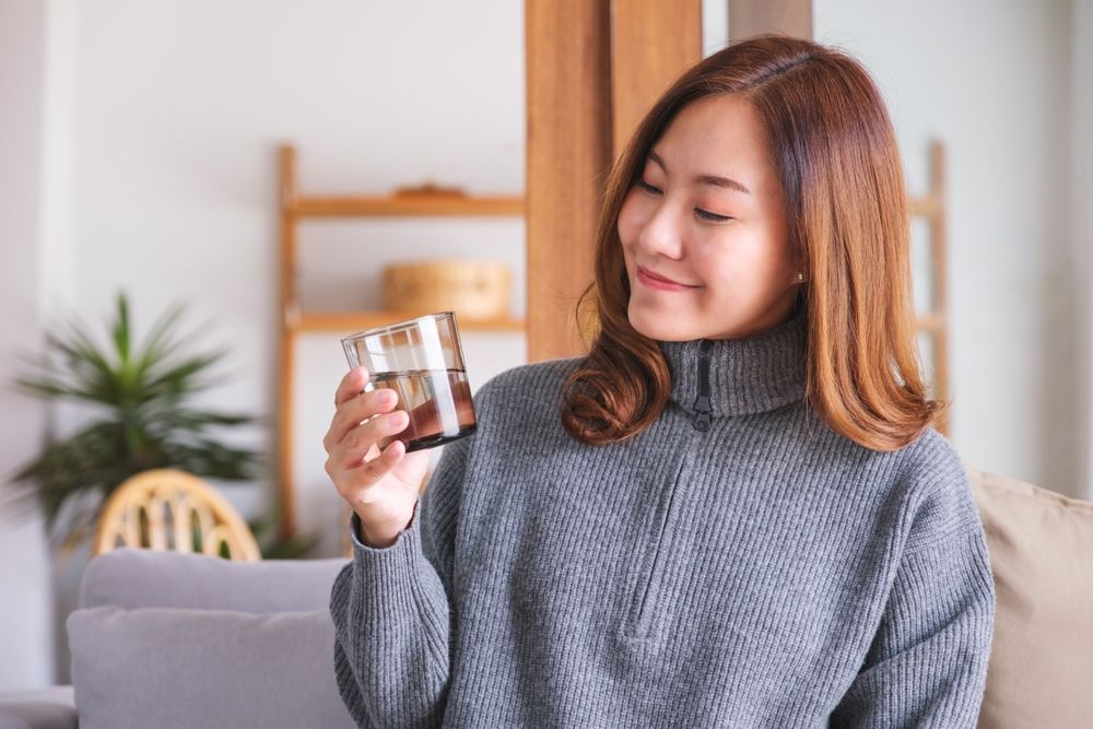 หญิงสาวจิบน้ำอุณหภูมิห้องตลอดทั้งวัน เพื่อดูแลอาการคอแห้งและฝืดคอ